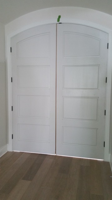 Clean white paneled arched interior shutter doors in Texas.
